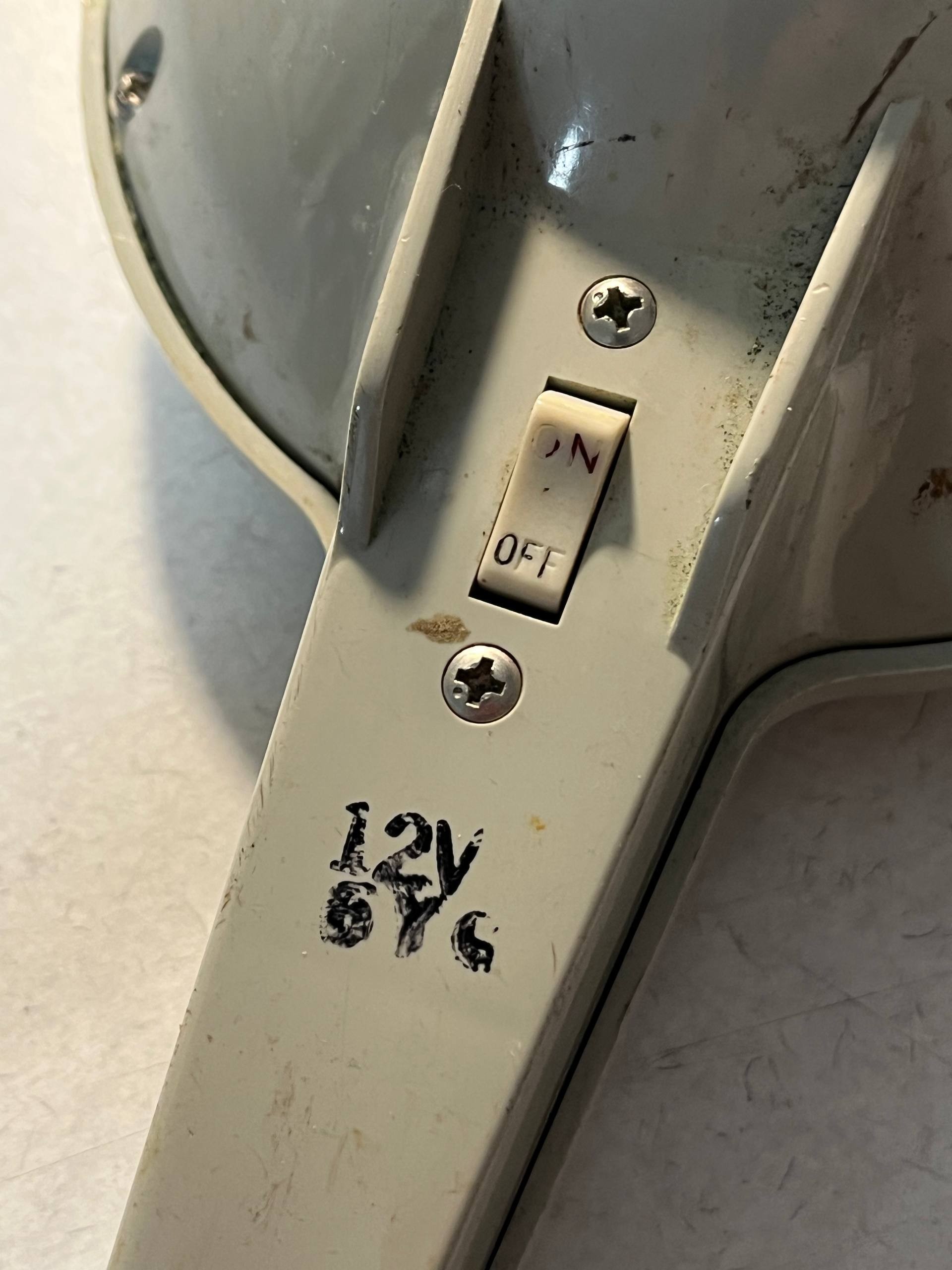 Light switch on the back of the torch, with ON and OFF markings. Under the switch, one can reaf 12V and something like 6Y6