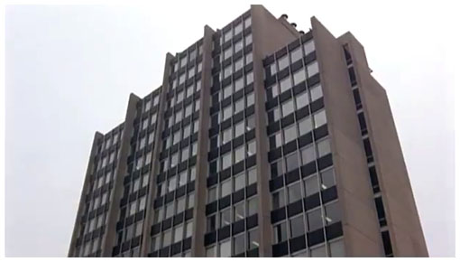 The old picture of the same office building with a facade that seems to be made from either concrete or brick.