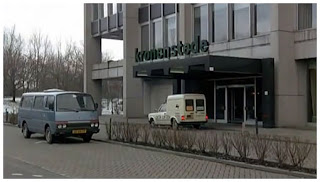 The old front lot and facade of the building, showing the name "kronenstede" above the entrance. One can also see two vans parked in front.